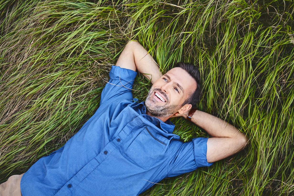 Relaxed happy man lying in grass stock photo