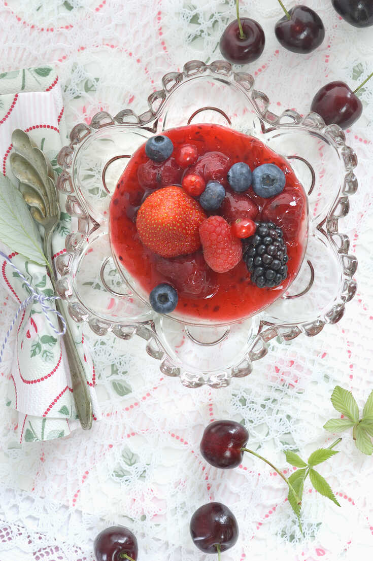 Rote Grütze mit ganzen Früchten in Glasschale, lizenzfreies Stockfoto