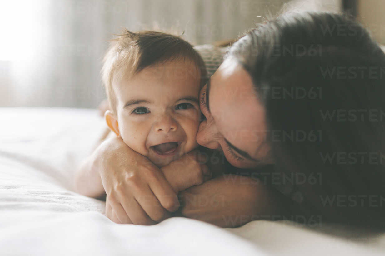 Mother and baby cuddling in bed at home stock photo
