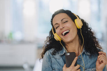 Happy woman listening music, singing and dancing, using smartphone and ...