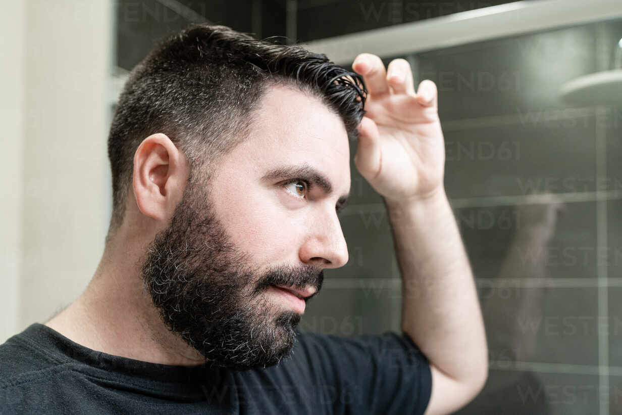 Self haircut. A man is combing his hair in the bathroom stock photo