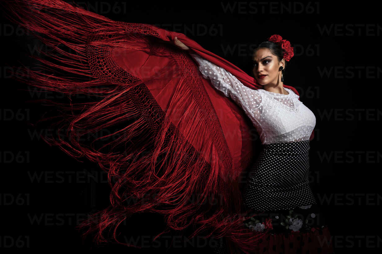 Seductive young Hispanic female in traditional costume performing sensual Flamenco dance and looking away stock