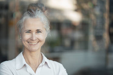 Mature woman with gray hair bun in cafe stock photo