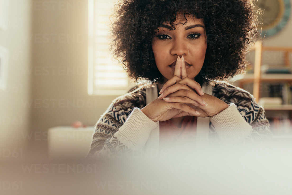 African woman with curly hair sitting at her desk and thinking. Portrait of  thoughtful female worker